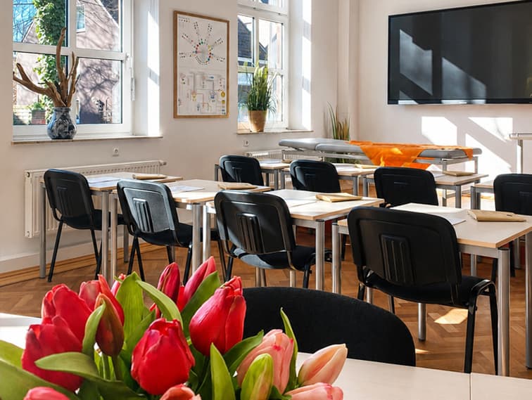 Seminarraum der Heilpraktikerschule Westfalen mit Tischen, Stühlen und Tulpen